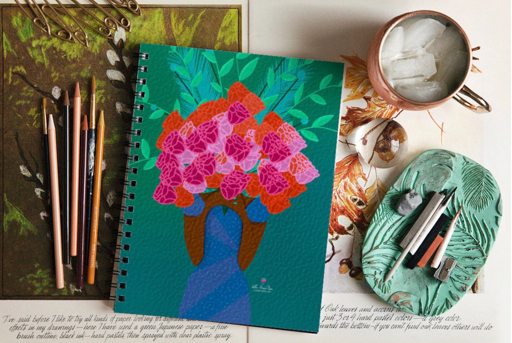 Notebook with floral design, pencils, and a mug on a table